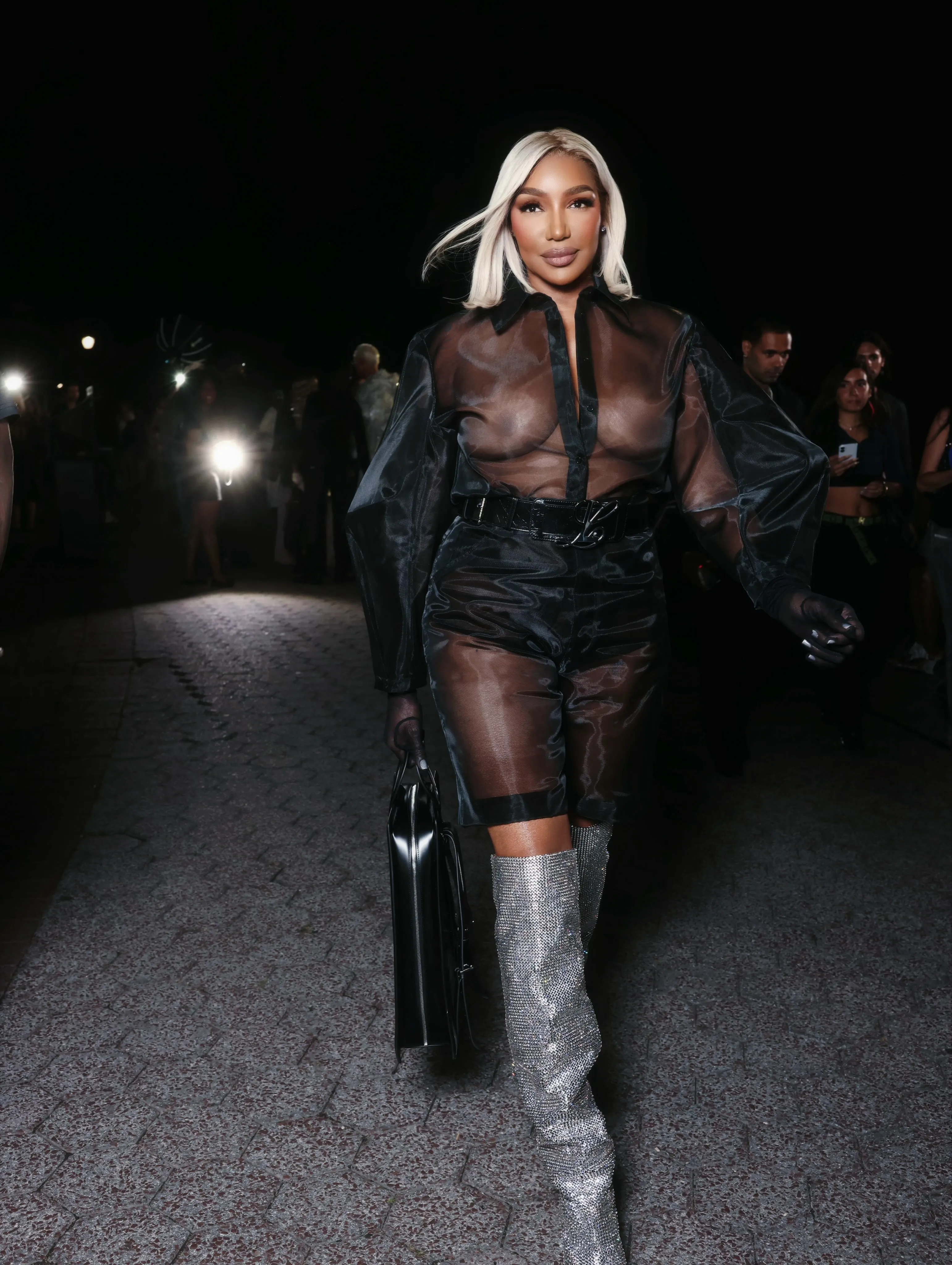 Nene Leakes in a sheer black shirt, shorts, and shimmering silver boots at the Luar show during NYFW.