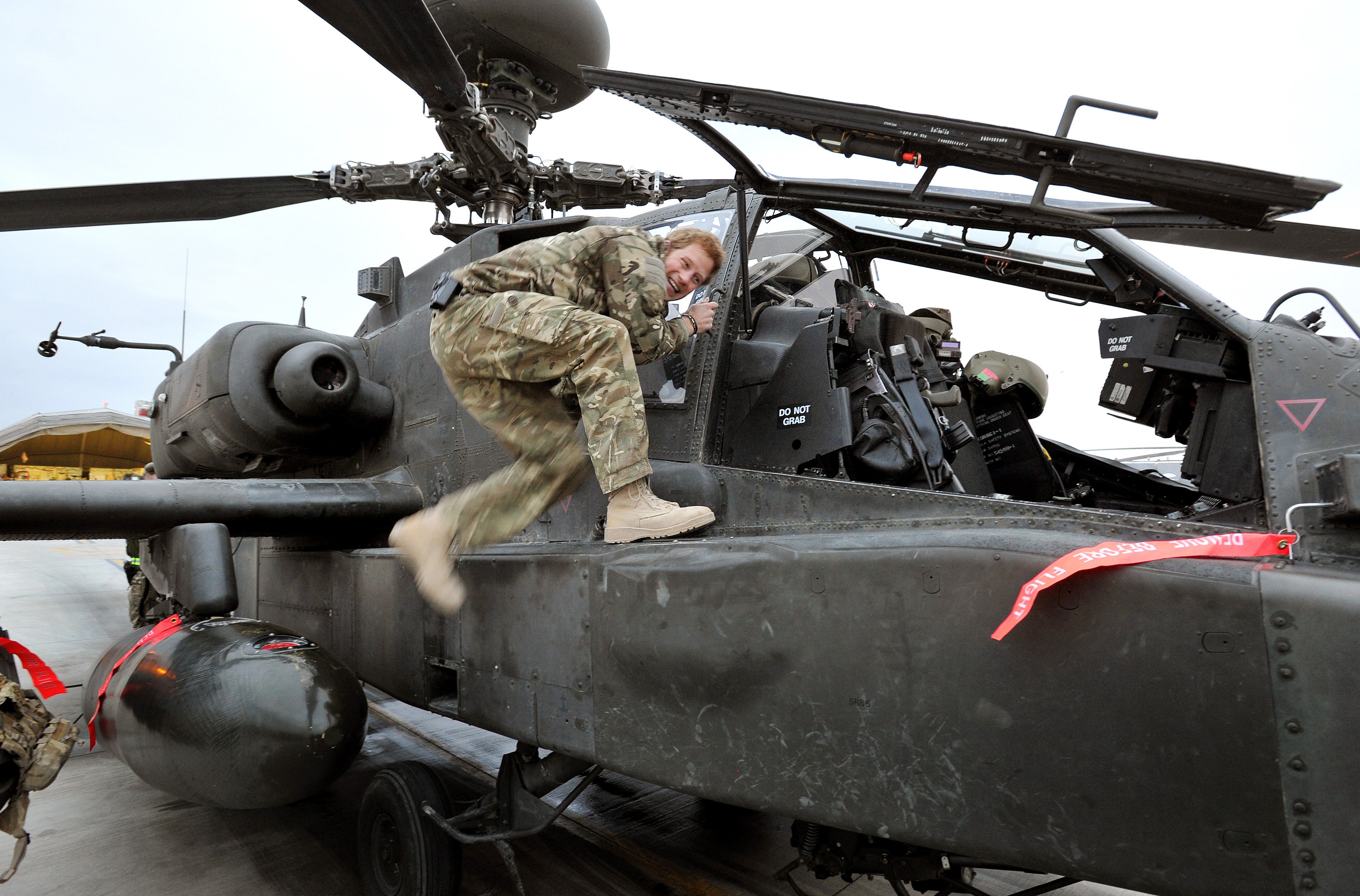 Prince Harry smiling as he steps into an Apache helicopter.