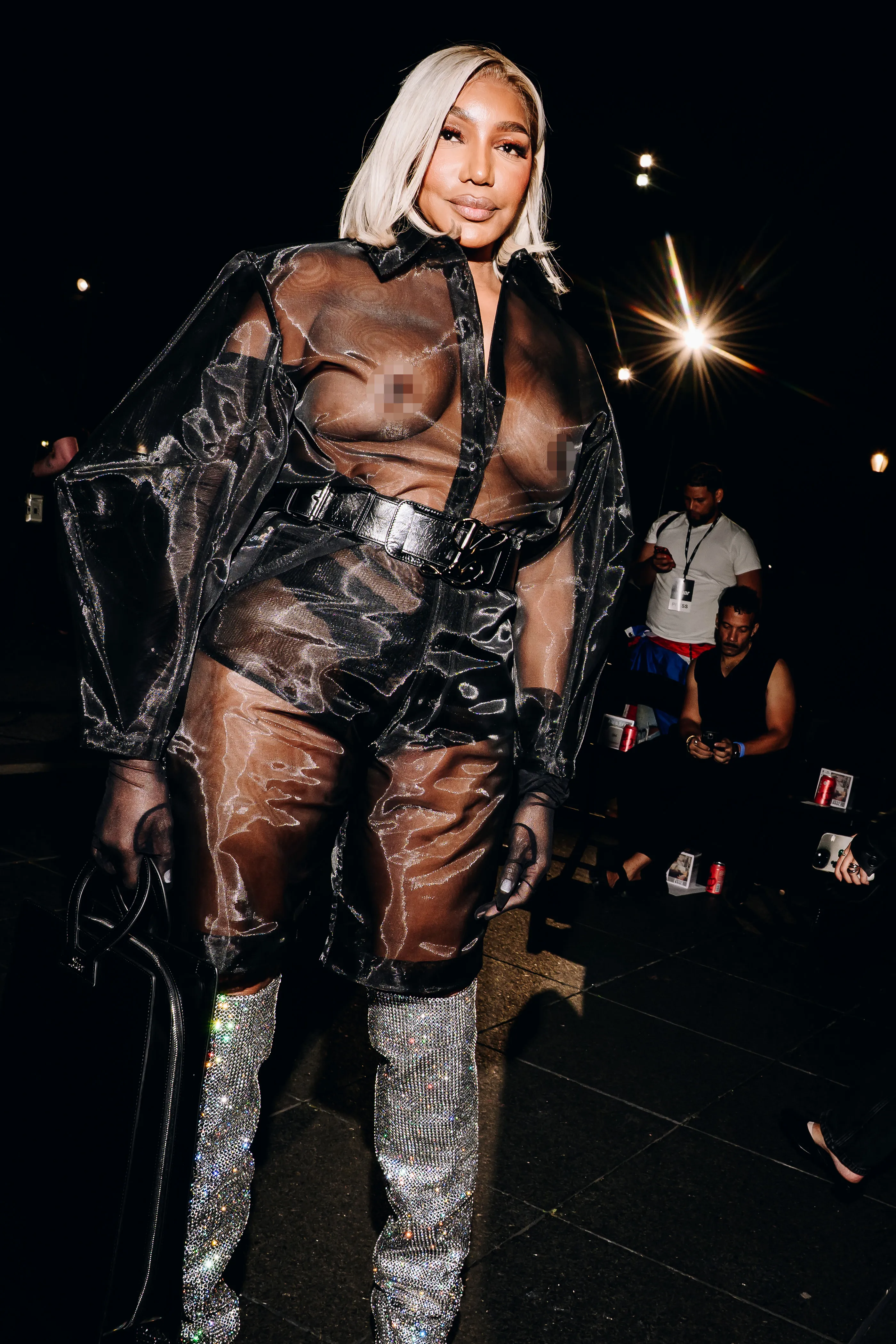Nene Leakes in a sheer black shirt, black shorts, and glittery silver boots poses for the camera.