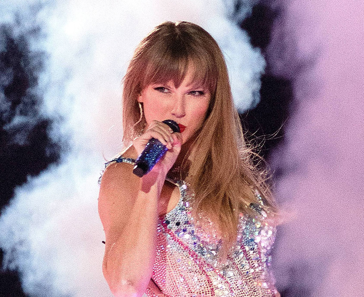 Taylor Swift performing on stage with a guitar under bright spotlighting